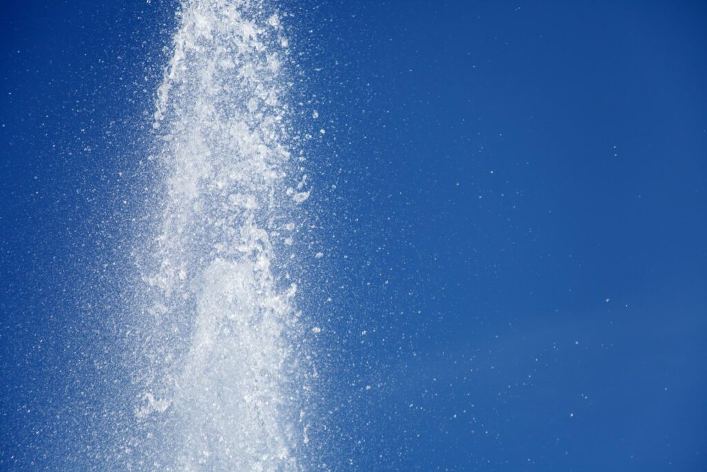 A powerful jet of water spraying into the air against a clear blue sky, serving as crucial home maintenance.