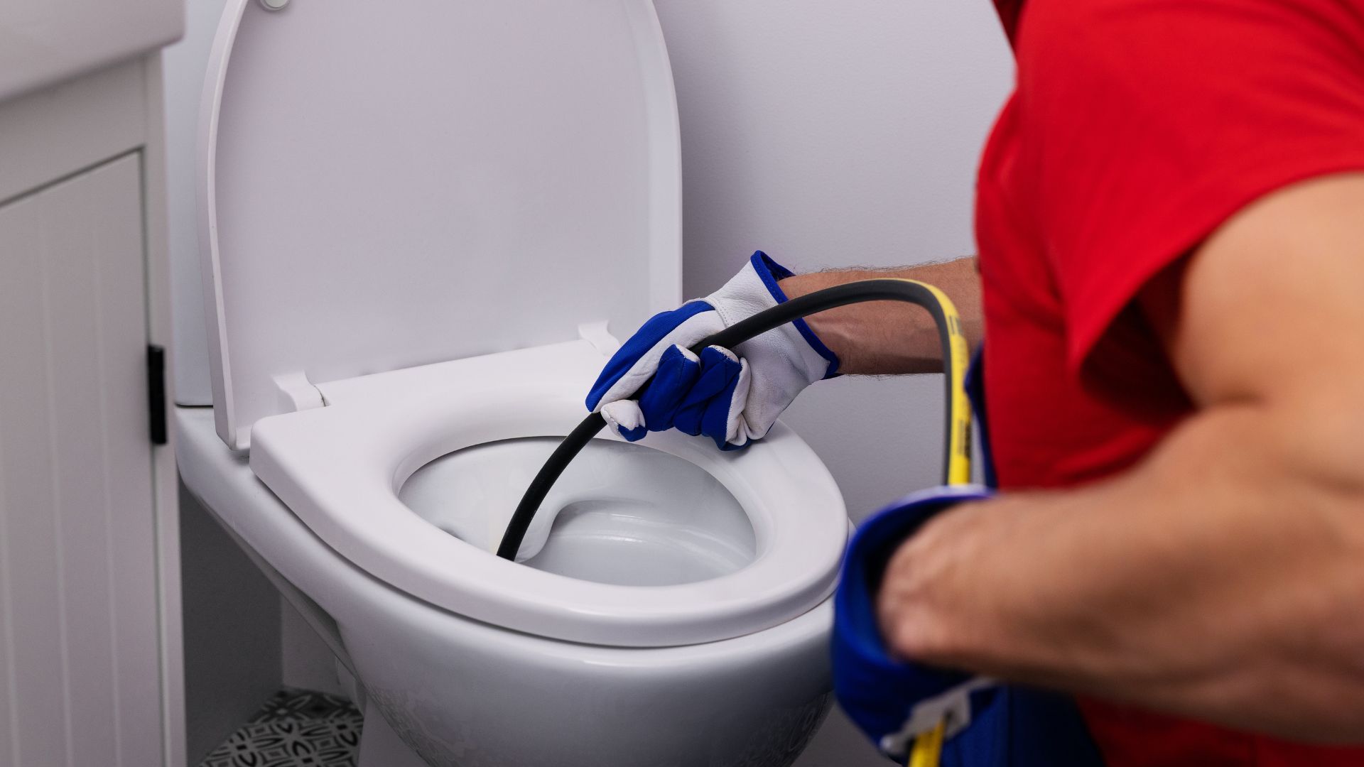Person unclogging a toilet with a hydro jetter