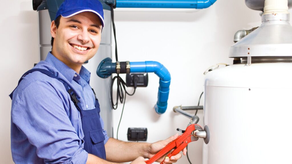 Plumber with a wrench working on a water heater installation.