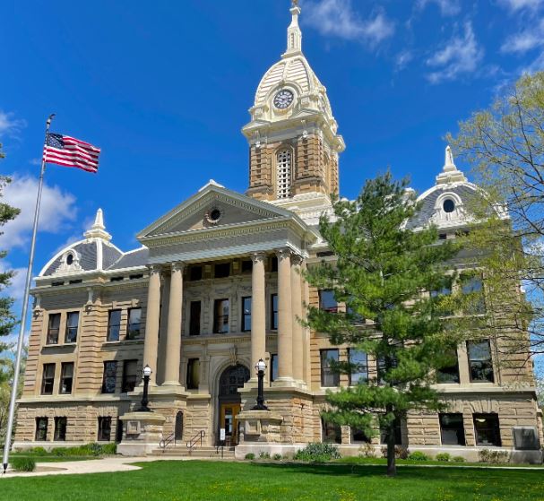 Historic courthouse building with a central clock tower under a blue sky.