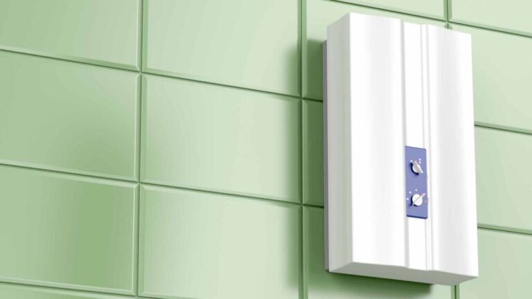 A white tankless water heater mounted on a light green tiled wall.