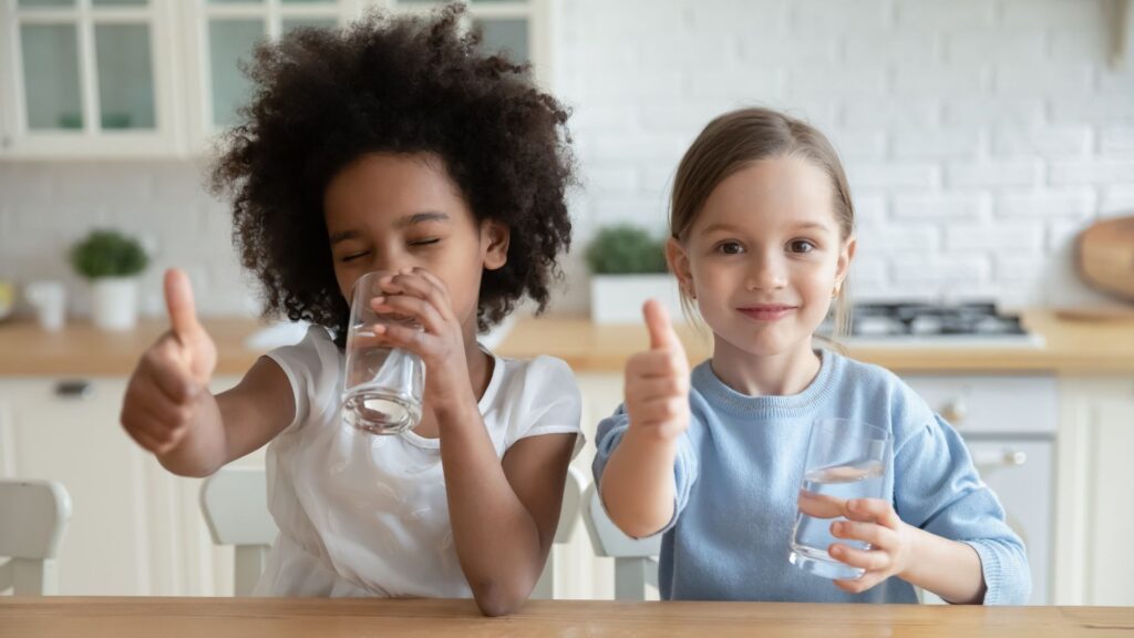 two kids at a table drinking water