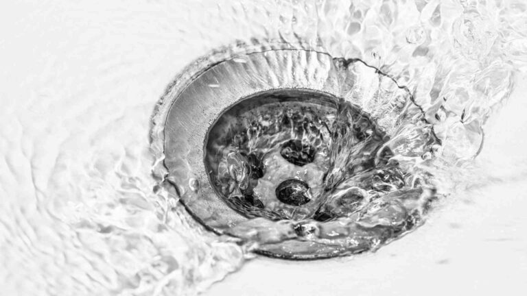 Water swirling down a metal sink drain