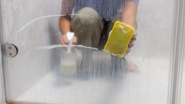 Person cleaning a glass shower door