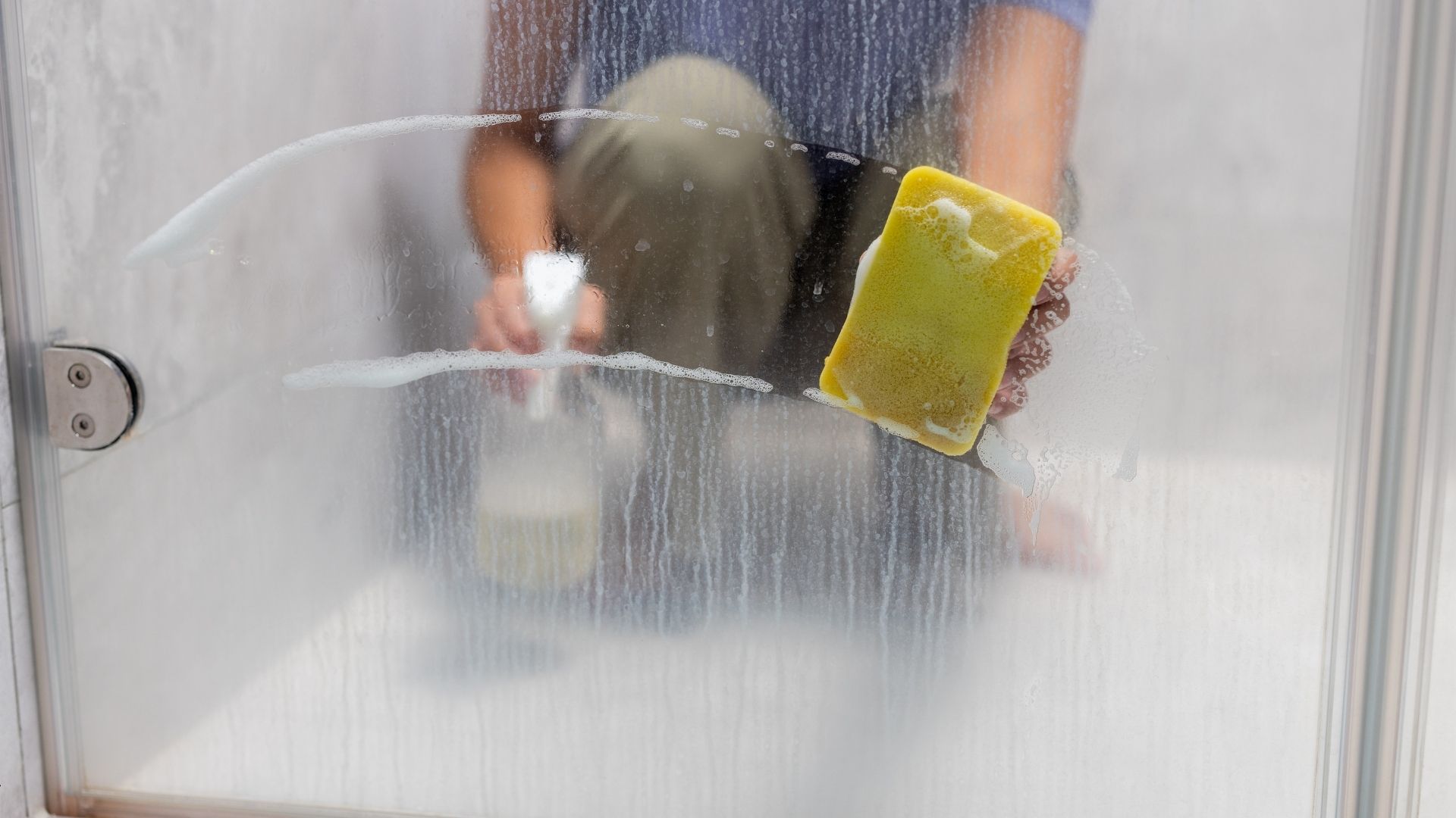 Person cleaning a glass shower door