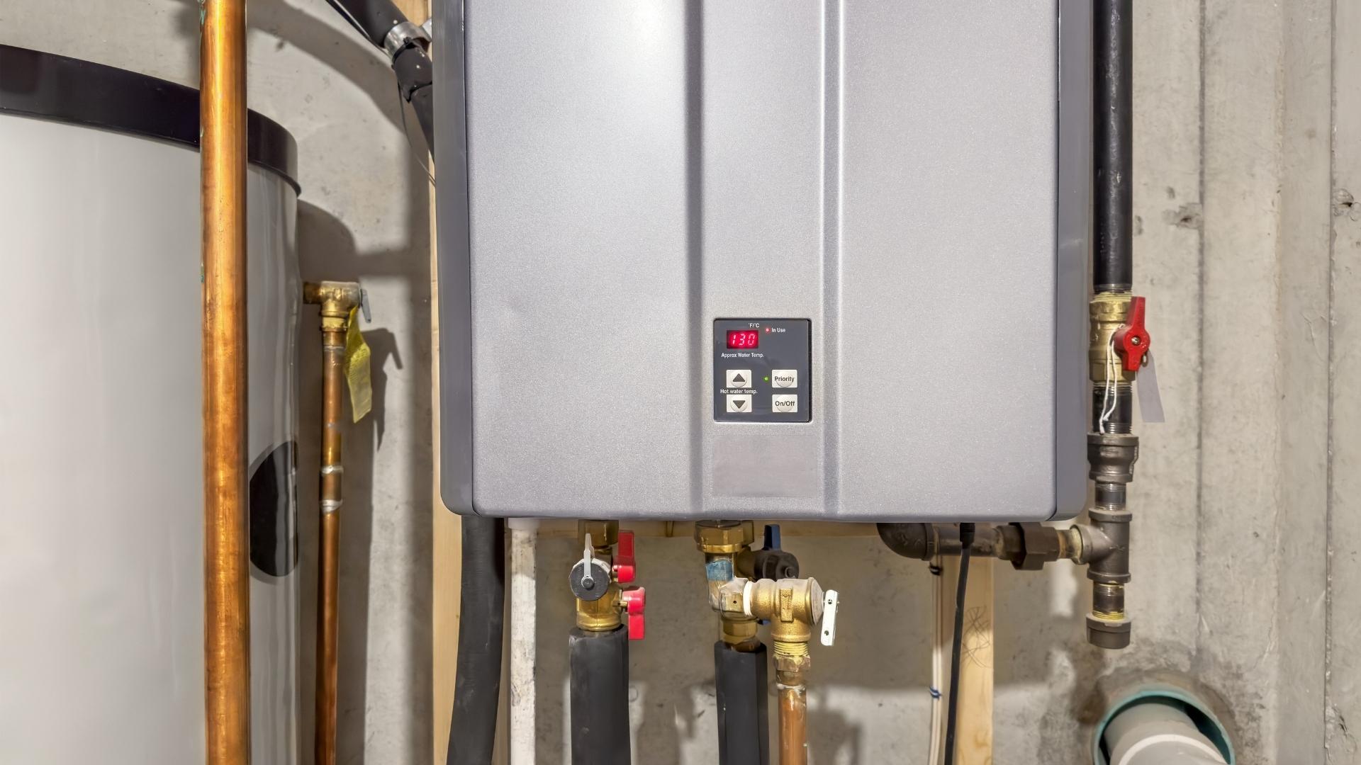 tankless water heater installation in michigan A close-up view of a wall-mounted tankless water heater with connected pipes and a digital display showing the temperature in a basement or utility room.
