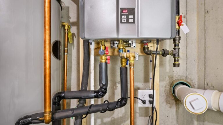 A tankless water heater mounted on a basement wall with visible copper pipes