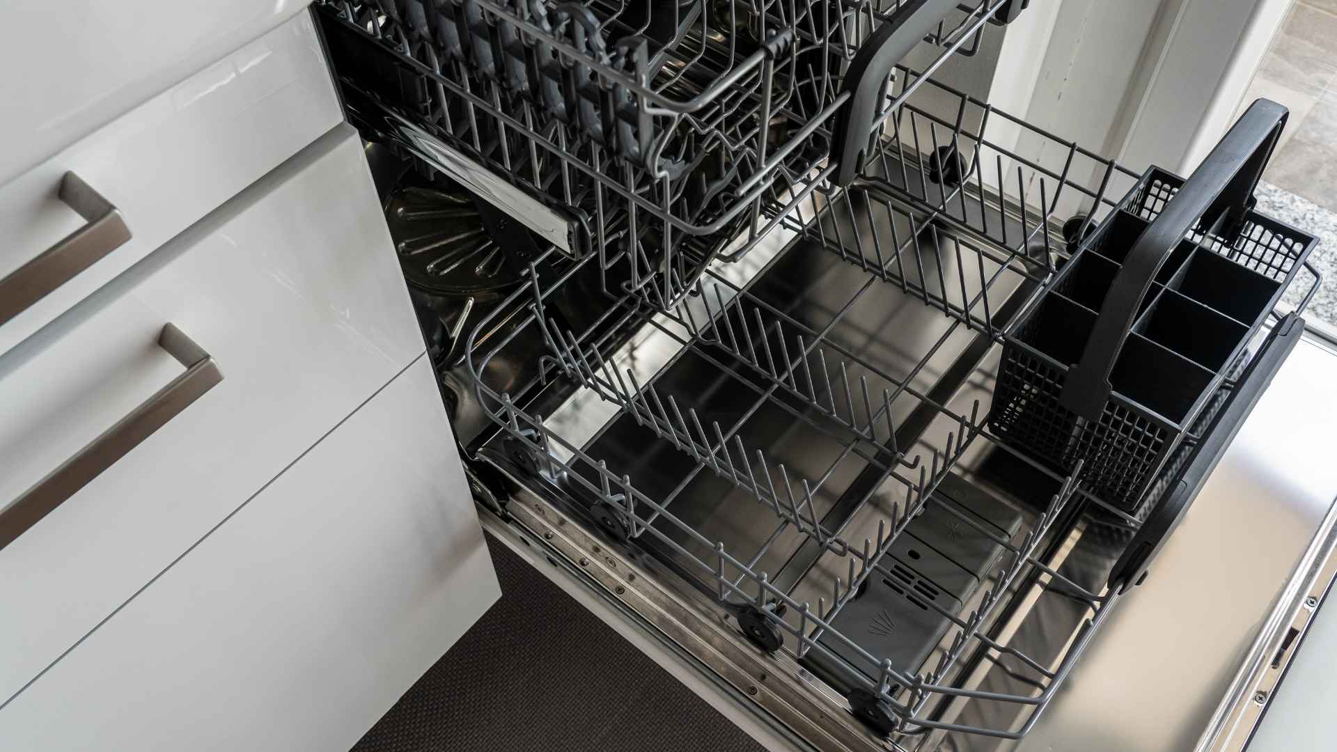 open dishwasher that is empty and clean next to white drawer cabinets in kitchen