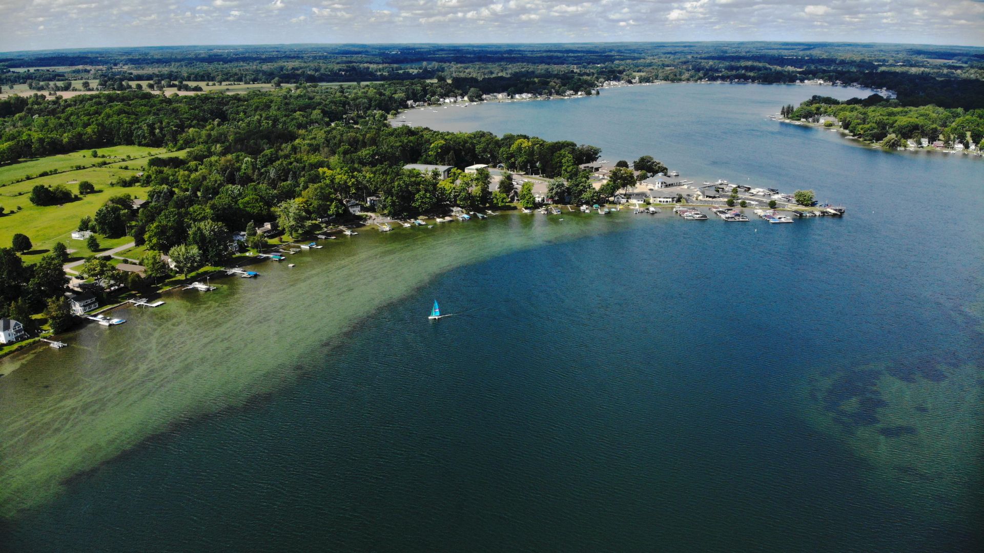 Aerial view of a lake with a sailboat in the water